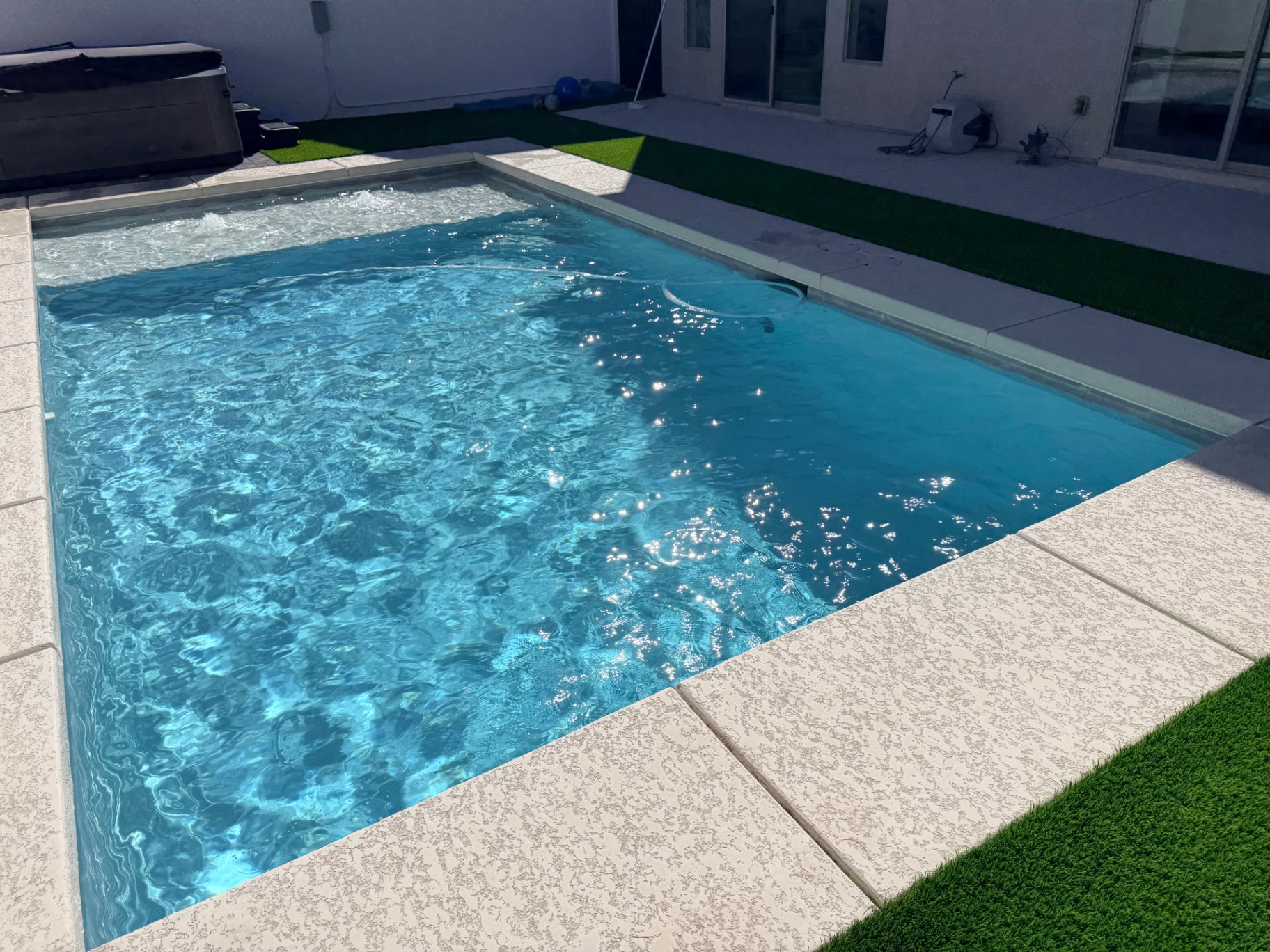 Freshly serviced rectangular backyard pool with sparkling water
