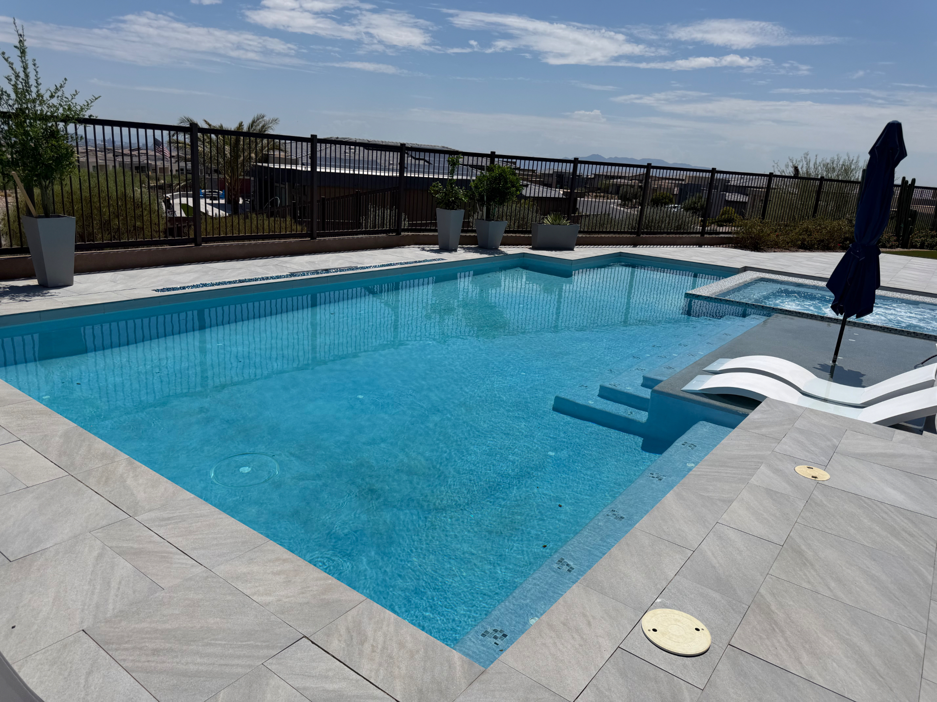 Bright blue residential pool and spa with a clean sun shelf